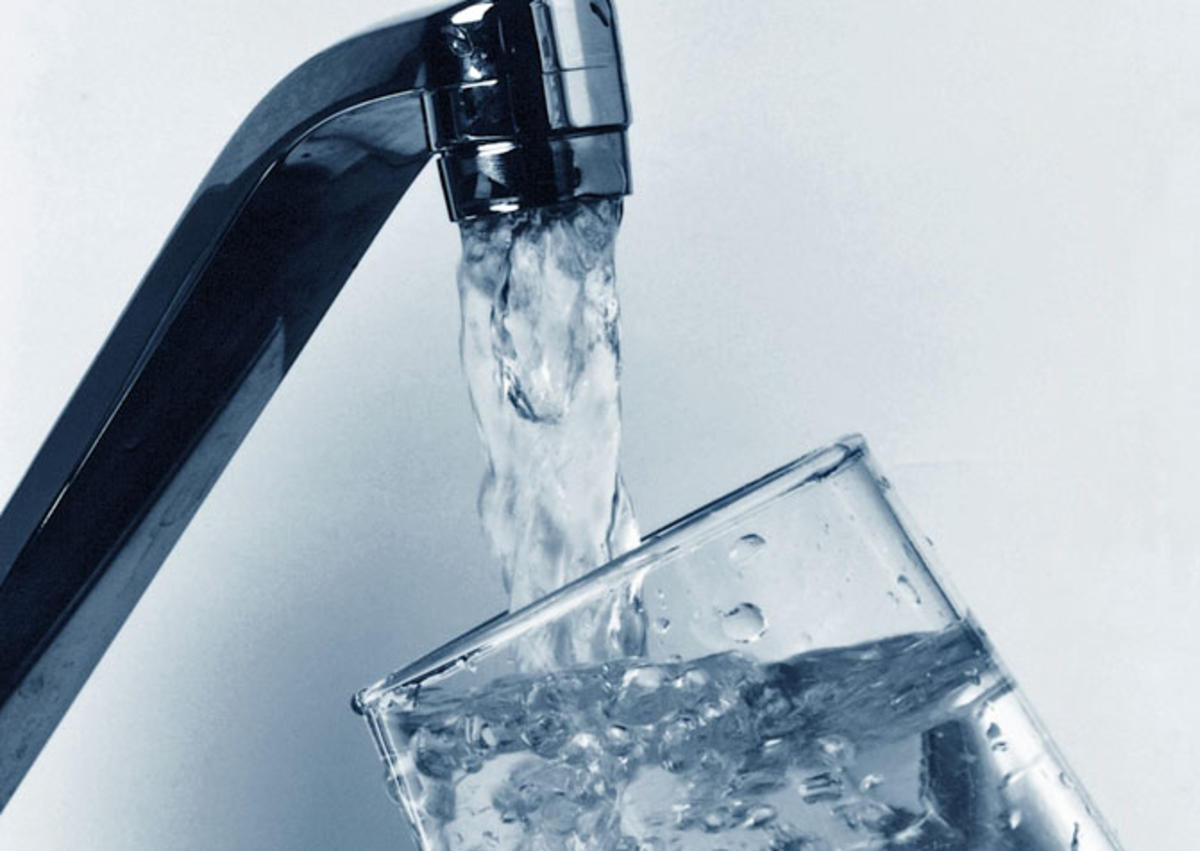 Silver faucet filling a glass of water